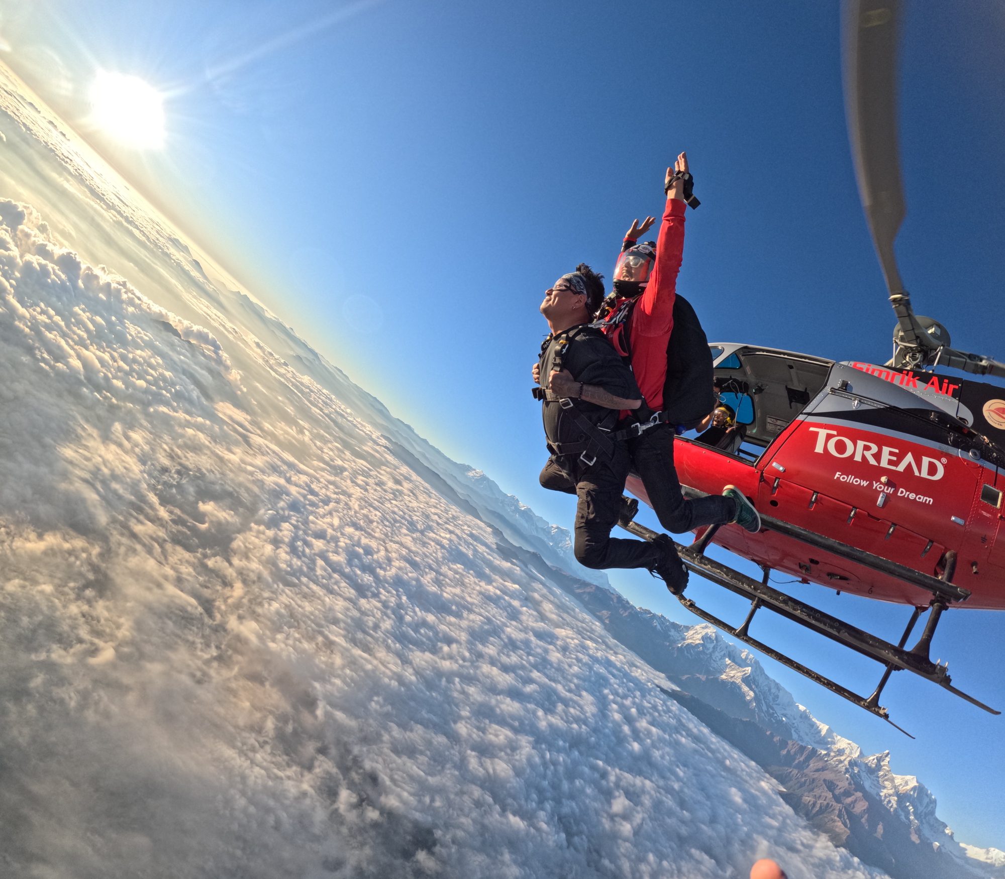 Skydiver in freefall above Phewa Lake with the Annapurna range behind